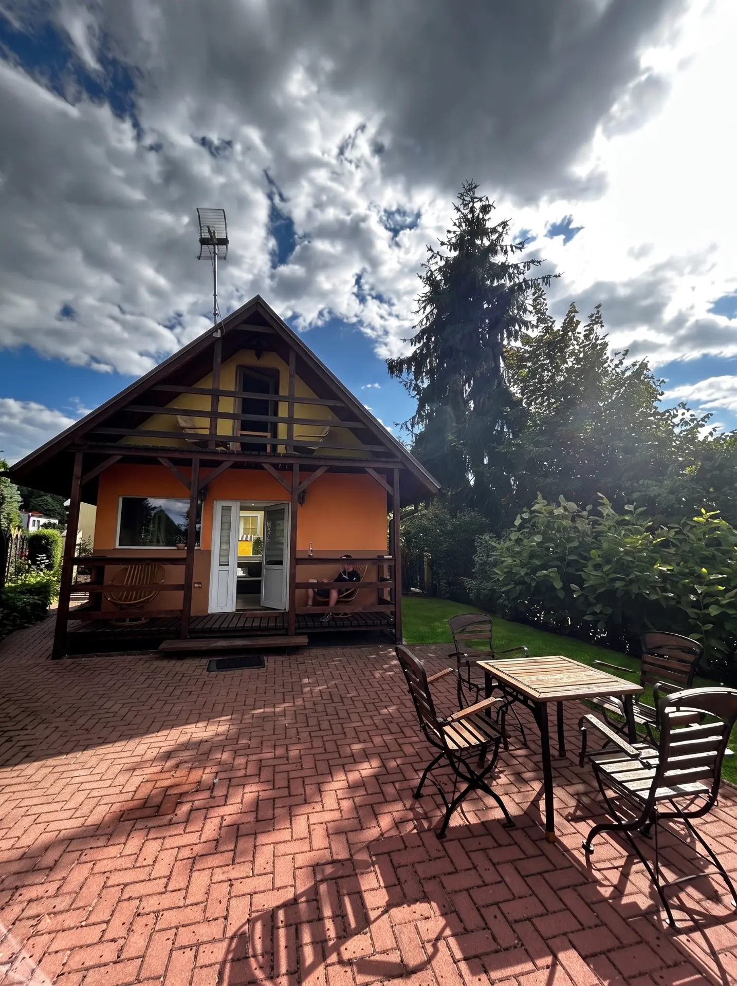 Drewniany domek z pomarańczową elewacją i zadaszonym tarasem